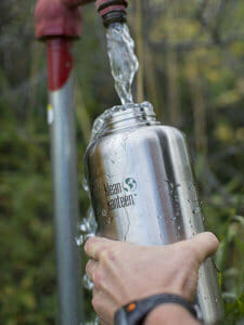 A person rinsing a bottle with water.